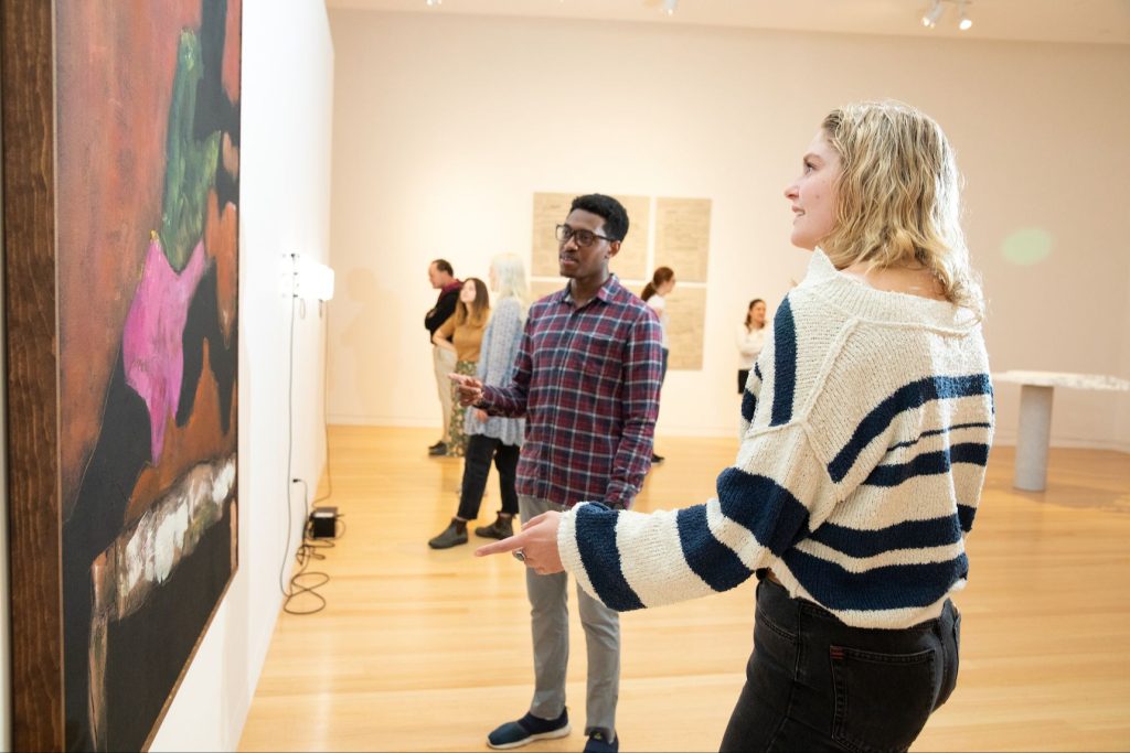 two students looking at a painting